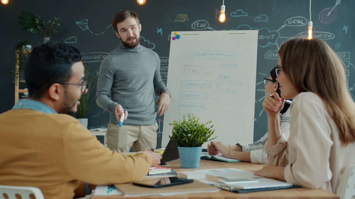 B2B sales team collaborating around a whiteboard to plan an account-based marketing strategy, by IDEAIFY Solutions