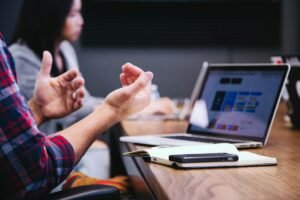 Sales professional comparing cold calling, cold email, and LinkedIn outreach during a team meeting, by IDEAIFY Solutions
